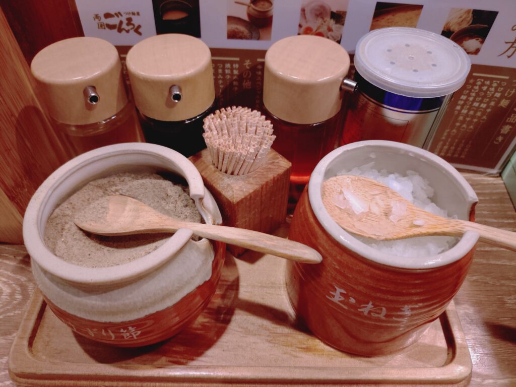 つけ麺屋ごんろくの卓上の刻みたまねぎと削り節